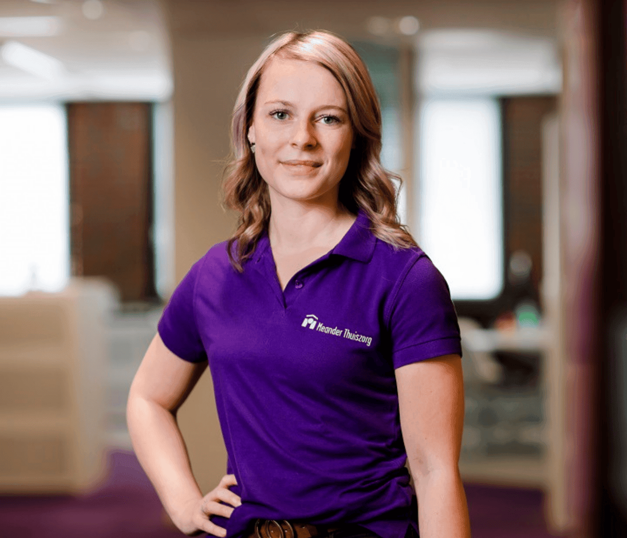 Jonge vrouw met een paarse polo van Meander Thuiszorg.