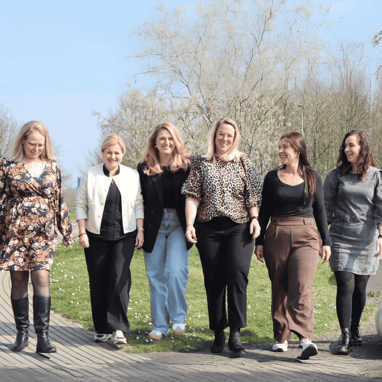 Zes vrouwen wandelen op een pad in het park.