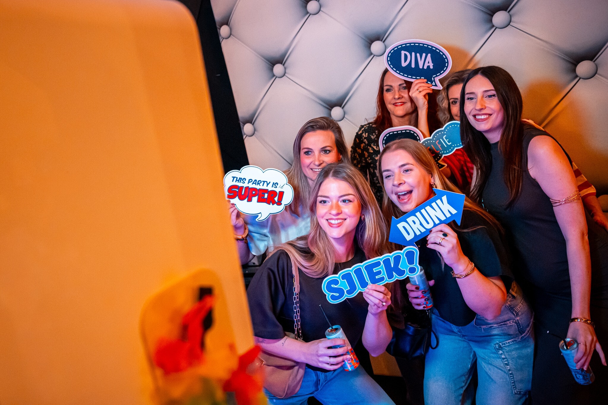 Zes vrouwen lachen naar een photobooth.